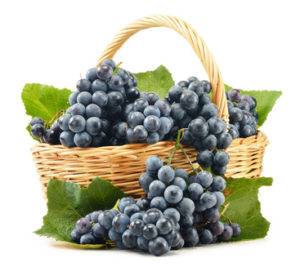 Wicker basket full of fresh red grapes isolated on white